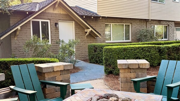 A patio area with a stone bench, a small table, and a fire pit.