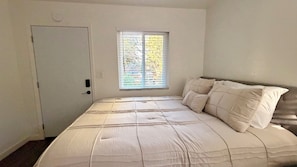 A bedroom with a bed, a window, and a door.