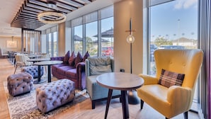 Ein moderner Lounge-Bereich mit Sitzgelegenheiten, großen Fenstern und Blick ins Freie.