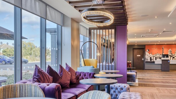 Ein modernes Interieur mit Sitzbereichen, einer Rezeption und großen Fenstern mit Blick auf die Straße.