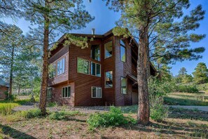 A multi-level wooden cabin surrounded by trees.