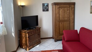 A living room with a television on a wooden dresser, a red sofa, and a wooden wardrobe. - Apartment "Liberty" (Paderno Dugnano)