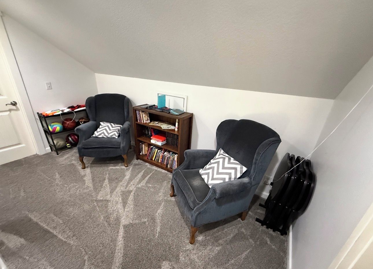 A room with two armchairs, a bookshelf, and a door.