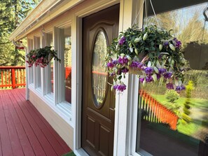 A porch with a red railing, a brown door, and hanging flower baskets. - Discover Your Serenity: A Hidden Gem Awaits at our Serene Cottage In The Woods (Kelso)