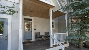A two-story house with a wooden porch, a staircase, and a small outdoor seating area. - Main Street Tri-plex close to everything! (Telluride)