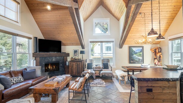 A spacious living room with a fireplace, leather sofa, and a stone-tiled floor. - Main Street Tri-plex close to everything! (Telluride)