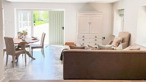 A modern living room with a sofa, a dining table set for four, and a cabinet. - The Old Stables 2 - UK35616 (Winterslow, near Salisbury)