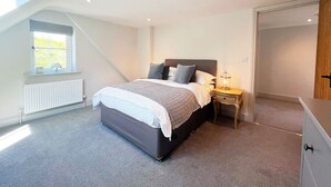 A bedroom with a bed, a nightstand, a window, a radiator, and a door. - The Old Stables 2 - UK35616 (Winterslow, near Salisbury)
