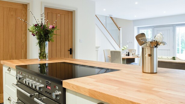 A modern kitchen with a built-in induction cooktop, stainless steel appliances, and a wooden countertop. - The Old Stables 2 - UK35616 (Winterslow, near Salisbury)