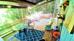A wooden deck with a table and chairs, surrounded by a wooden railing and a view of trees. - Make Casa Cabina Your Next Vacation Rental (Henderson)