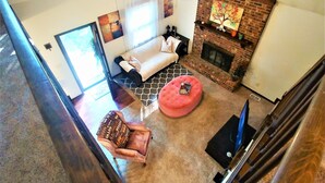 A living room with a sofa, ottoman, and fireplace. - Make Casa Cabina Your Next Vacation Rental (Henderson)