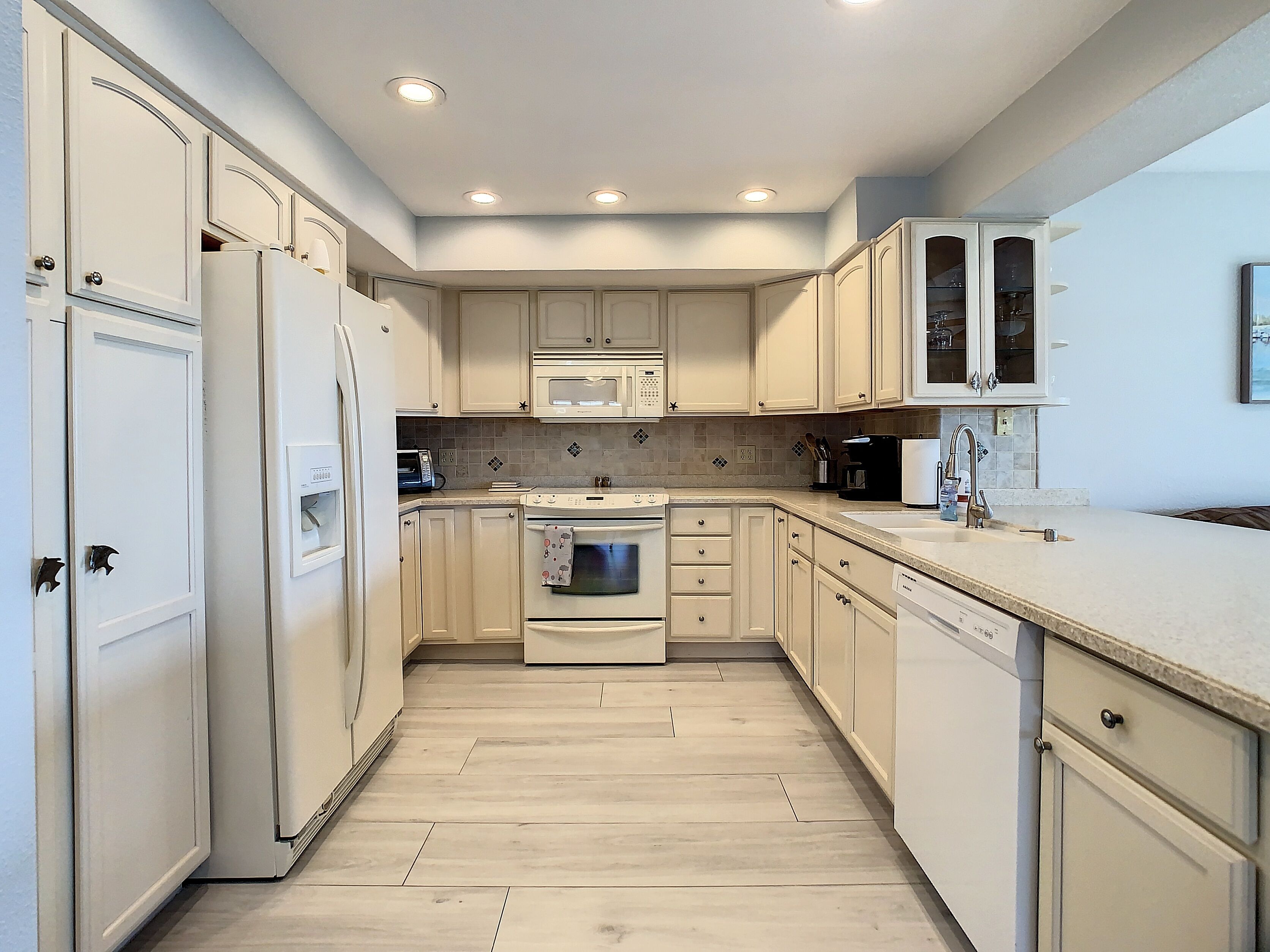 A kitchen with white cabinets, a microwave, an oven, and a dishwasher.
