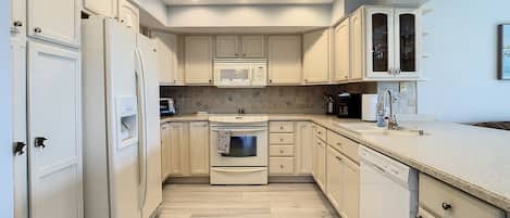 A kitchen with white cabinets, a microwave, an oven, and a dishwasher.