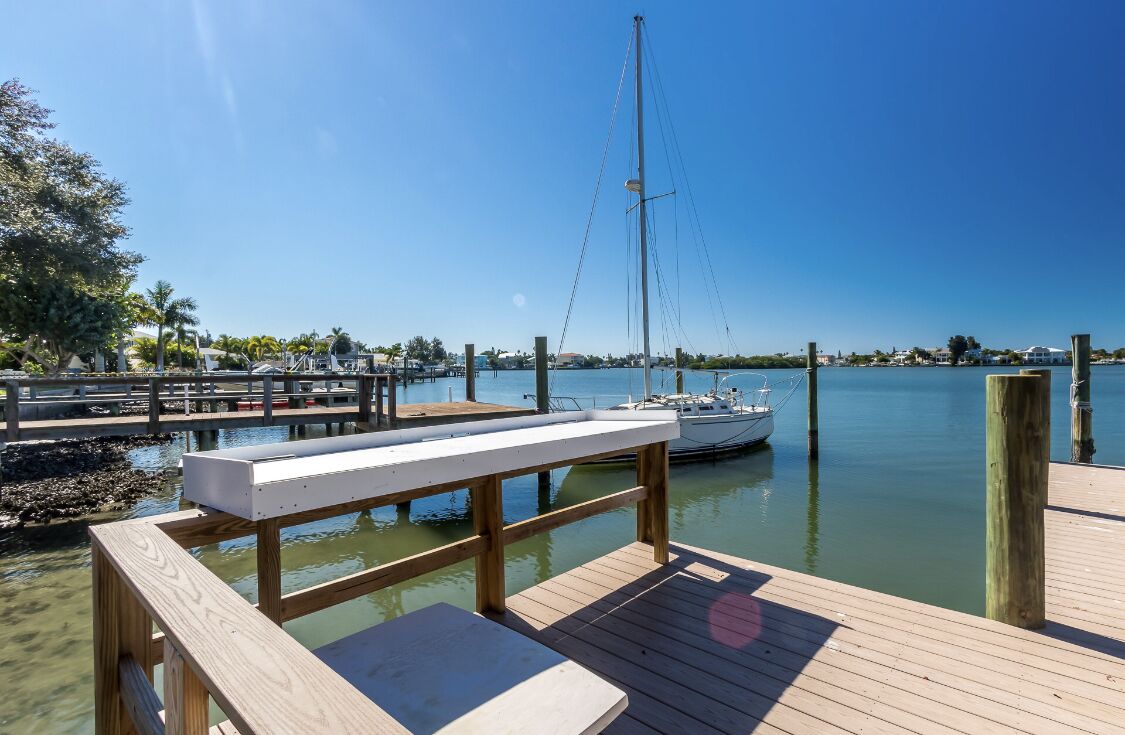 A wooden dock with a bench and a sailboat docked at a marina.