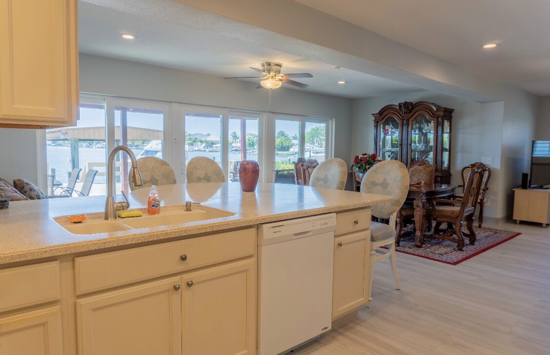 A spacious kitchen with a large island, a dishwasher, and a dining area with a wooden table and chairs.