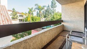 Un balcon avec vue sur les palmiers et les immeubles.