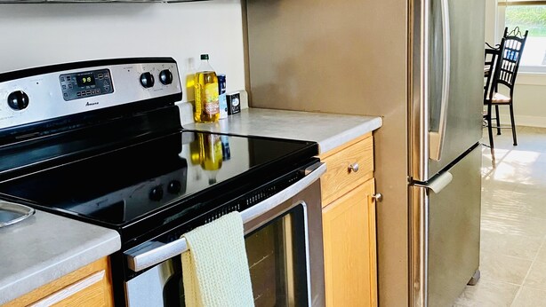 A modern kitchen with stainless steel appliances, wooden cabinets, and a tiled floor. - Cozy Home, Minutes from Killington! Washer/Dryer & Free Disney+/Peacock! (Mendon)
