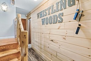 En trævæg med teksten "WHISTLING WOODS" og en trætrap.