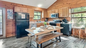 A wooden cabin-style kitchen with a dining table set for four, a refrigerator, microwave, and a coffee maker. - Spring Break! Games~Secluded & Close~Nerf~Foosball~HotTub~One Step Entry (sevierville)