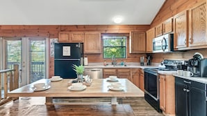 A kitchen with wooden cabinets, a dining table set with plates, a refrigerator, and a stove. - Spring Break! Games~Secluded & Close~Nerf~Foosball~HotTub~One Step Entry (sevierville)