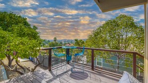 A wooden deck with a blue metal table and chairs, overlooking a scenic landscape with trees and a distant view of hills. - The Agave House | Mountain Views & Pool (La Mesa)