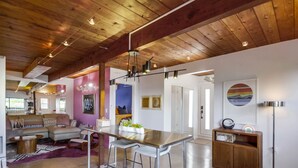 A spacious living area with a wooden ceiling, a kitchen island with stools, a sofa, and a coffee table. - The Agave House | Mountain Views & Pool (La Mesa)