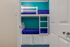 Une chambre avec des lits superposés, des murs de couleur turquoise et des meubles blancs.