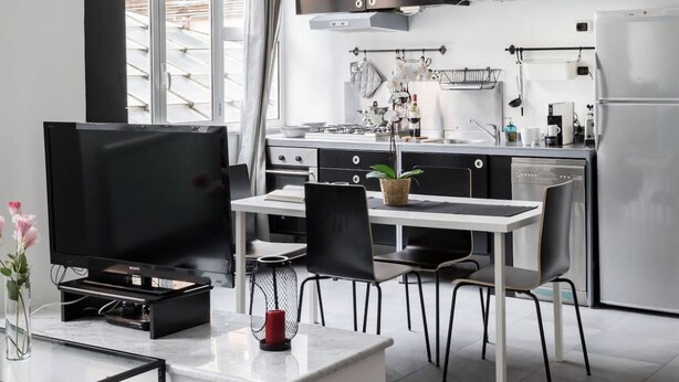 A modern kitchen with a dining area, featuring a TV, a dining table, and chairs. - New! Trevi Fontain Modern Loft Apartment  (Roma)