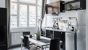 A modern kitchen with a dining area, large windows, and a view of the outside. - New! Trevi Fontain Modern Loft Apartment  (Roma)