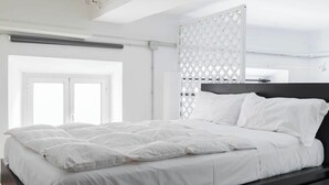 A modern bedroom with a large bed, a dark headboard, and a window with a view of the outside. - New! Trevi Fontain Modern Loft Apartment  (Roma)
