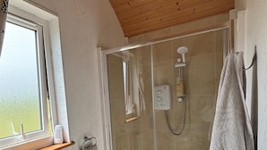 A bathroom with a shower, toilet, and a window. - The Lazy Llama Shepherd Hut & Sauna (Ballyshannon)