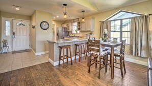 A spacious kitchen with a large island, wooden bar stools, and a dining table.