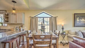 A dining area with a wooden table, chairs, and a kitchen counter.