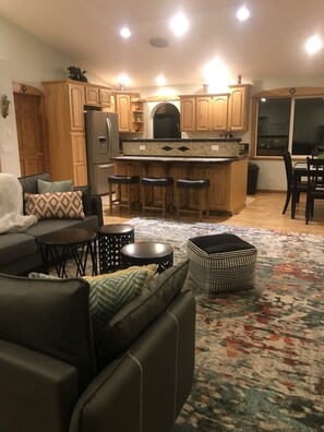 Relax in this stylish living space with a sofa, coffee table, and ottoman, plus a fully equipped kitchen with a refrigerator and bar area.