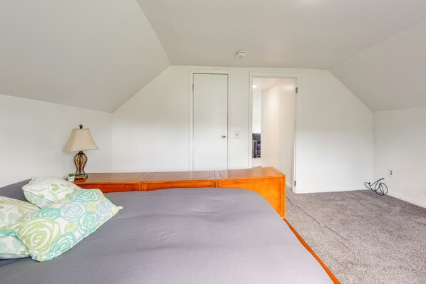 A bedroom with a bed, a nightstand, a lamp, and a door leading to another room.