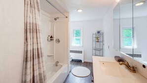 Un baño moderno con una bañera, ducha, inodoro y lavabo.