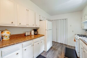A kitchen with white cabinets, a refrigerator, a coffee maker, and a stove.