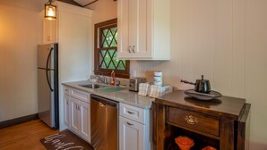 A compact kitchen with white cabinets, a stainless steel refrigerator, a dishwasher, a window with a diamond pattern, and a wooden countertop with a coffee maker and a pot. - Bavarian-Style Cottage on Beech Mountain (Beech Mountain)