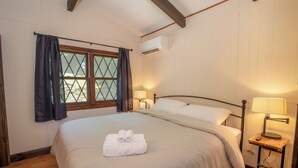 A neatly made bed with a set of towels, a bedside table with a lamp, and a window with curtains. - Bavarian-Style Cottage on Beech Mountain (Beech Mountain)
