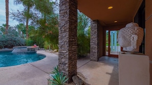 A pool area with stone pillars, a statue, and lush greenery.