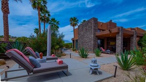 A modern house with a stone facade, outdoor seating area with lounge chairs, and a decorative fountain. - Luxury Modern Oasis w/ Salt Pool, Spa & Zen Yard (Rancho Mirage)