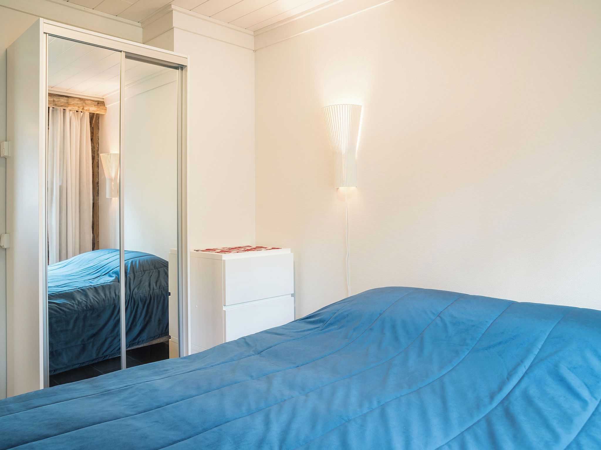 A bedroom with a bed, a wardrobe, and a bedside table.