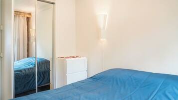 A bedroom with a bed, a wardrobe, and a bedside table.