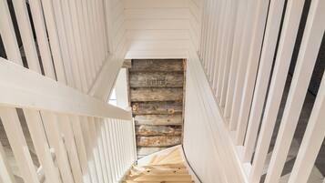 Eine Holztreppe mit Blick auf eine rustikale Blockbauwand im unteren Bereich.