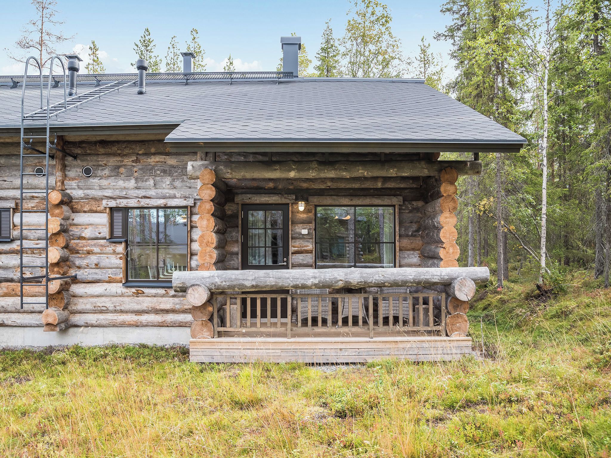 A log cabin with a porch, windows, and a chimney.
