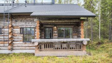 A log cabin with a porch, windows, and a chimney.
