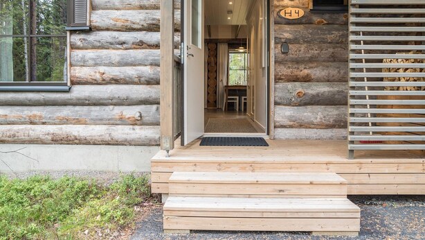 Une cabane en rondins avec une porte d’entrée en bois, une plaque portant le numéro « 4 » et un escalier menant à l’entrée.