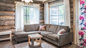 L’intérieur d’un chalet confortable, avec une banquette d’angle grise, une table basse en bois et un luminaire suspendu.
