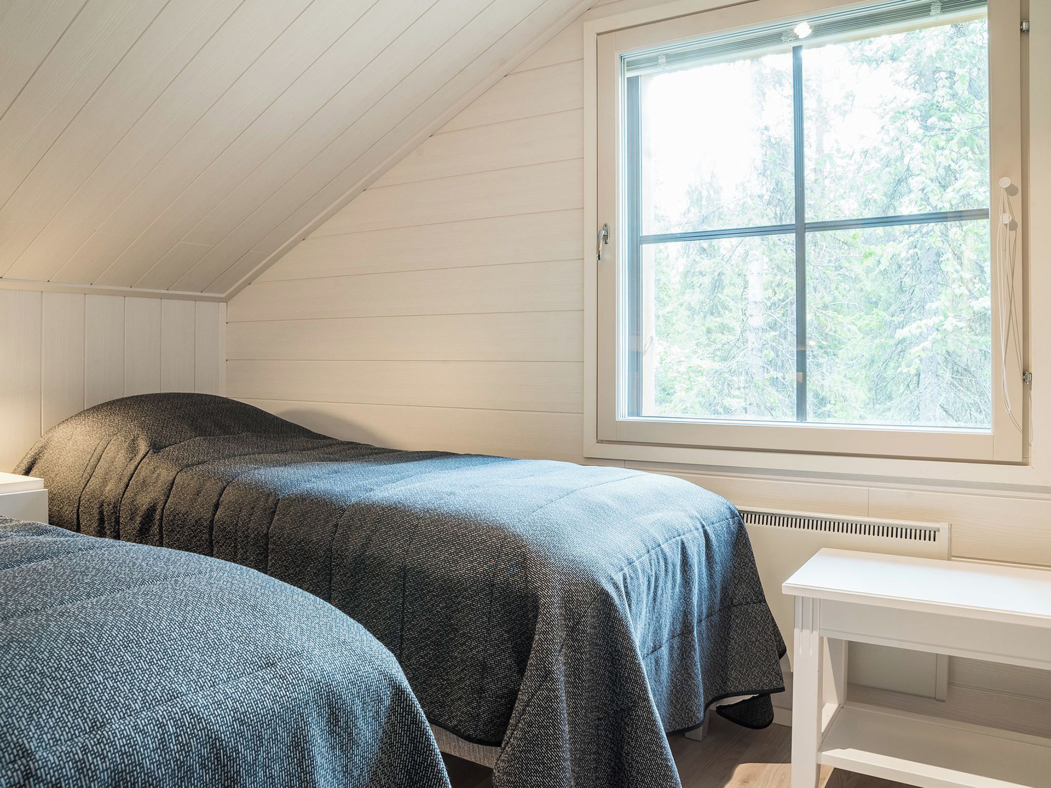 A room with two beds, a window, and a white table.