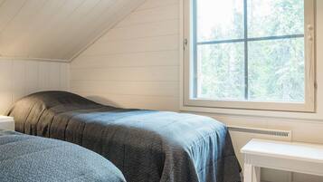 A room with two beds, a window, and a white table.